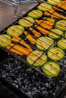 Chopped zucchini and carrots roasting on fire seasoned with aroma herbs and spices. Delicious fresh vegetables grilling on barbecue smoker grid. Diet vegan bbq. Outdoor recreation in backyard photo