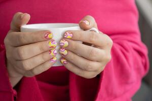 Pastel softness colorful manicured nails. Woman holding white cup of coffee or tea showing her new summer manicure in colors of pastel palette. Simplicity decor fresh spring vibes earth-colored neutral tones design photo