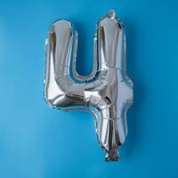 4 four metallic balloon isolated on blue background. Greeting card silver foil balloon number Happy birthday holiday concept. Copy space for text. Celebration party congratulation decoration photo