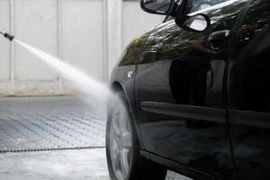 Lavado lujo negro coche en sin contacto coche lavar. limpieza el detalles de coche. Lavado sedán coche con espuma autoservicio y alto presión agua. limpieza y orden en urbano ambiente foto