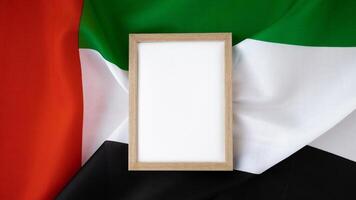 Empty white paper frame template National symbol of UAE. United Arab Emirates small flag with Peregrine falcon on neutral beige background. Copy space for your text. Concept of National day Independence photo