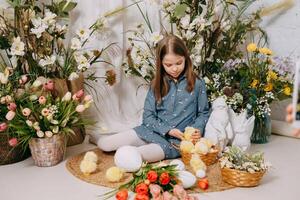 Two girls in a beautiful Easter photo zone with flowers, eggs, chickens and Easter bunnies. Happy Easter holiday.