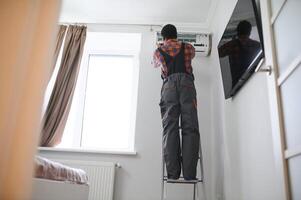 Young African Male Technician Repairing Air Conditioner photo