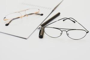 Blank notebook with pen are on top of white office desk table. Top view with copy space, flat lay. photo