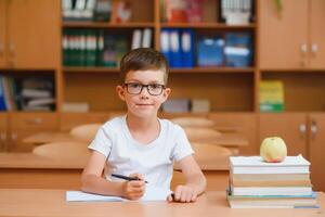 pequeño niño escritura con vistoso lápices, adentro. elemental colegio y educación. niño aprendizaje escritura letras y números. foto