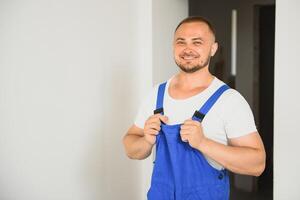 retrato de joven personal de mantenimiento en pie en blanco antecedentes con Copiar espacio. reparador vistiendo ropa de trabajo uniforme. foto