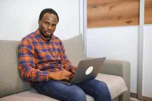 Connecting with an online world. Shot of a happy young man using a laptop while relaxing at home photo