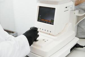 Modern medical equipment. Close up of ophthalmologist using auto refractometer while examining child eyes. photo