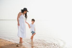 mother and son walking on sunset beach photo