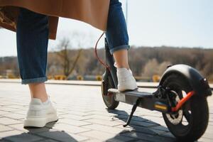 Cropped on woman legs feet riding on electric kick scooter in city photo