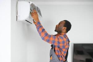 profesional reparador instalando aire acondicionador en un habitación foto