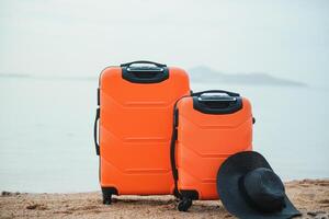 Color travel suitcase on sandy beach with turquoise sea background, summer holidays concept photo