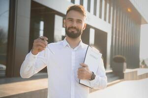 Real estate agent holding key on blurred background, closeup photo