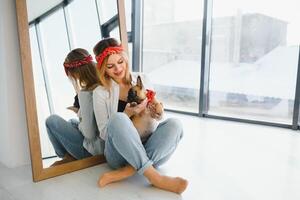 Cheerful young woman holding her big puppy with black nose and laughing. Indoor portrait of smiling girl posing with french bulldog photo