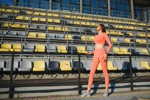 deporte y recreación concepto. niña en Deportes vestir posando a estadio antes de aptitud ejercicio. foto