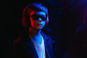 teen boy listening to music with headphones, neon light trending portrait. Looks at the camera photo