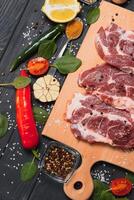 Raw pork meat on wooden cutting board at kitchen table for cooking pork steak roasted or grilled with ingredients herb and spices , Fresh pork. photo