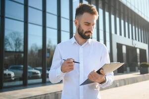 Businessman or real estate agent ready to discuss business and stands against new building photo