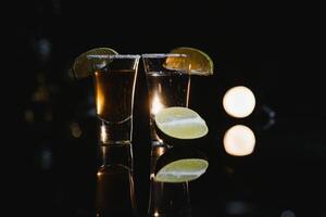 Tasty alcohol drink cocktail tequila with lime and salt on vibrant dark background. Closeup. photo