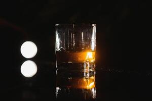 Whiskey glass black background shiny photo