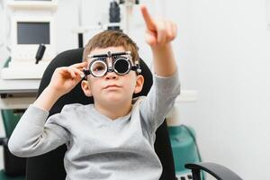 Cheerful child boy in glasses checks eye vision pediatric ophthalmologist photo