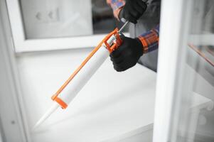 a african repairman repairs, adjusts or installs metal-plastic windows in the apartment photo