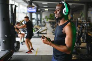 africano americano hombre escuchando motivacional música terminado auriculares mejorando calidad de rutina de ejercicio foto