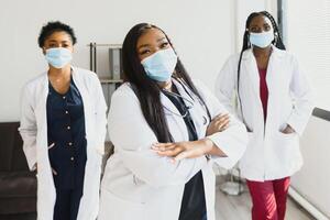 grupo de africano americano hembra doctores en protector mascaras en su caras. foto