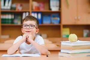 education and school concept - smiling little boy with many books at school photo