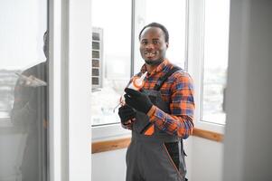 Workman in overalls installing or adjusting plastic windows in the living room at home photo