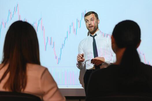 Man is standing near projector and showing graphs and business graphs. photo