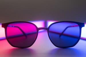 Stylish sunglasses shot using pink and blue abstract colored lighting with copy space. photo
