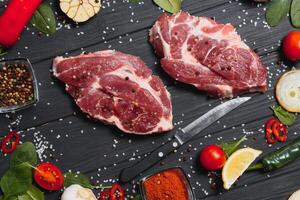 Raw pork meat on wooden cutting board at kitchen table for cooking pork steak roasted or grilled with ingredients herb and spices , Fresh pork. photo