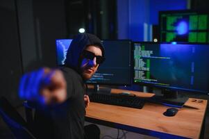 hacker sentado a escritorio en oscuro atmósfera. un computadora programador o hacker anónimo computadora hacker foto