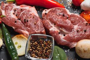 Raw pork meat with spices and vegetables on wooden table. photo