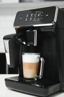 Modern coffee machine with glass cup of latte on white marble countertop in kitchen photo