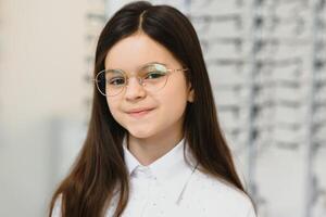 Cute little girl with new glasses in shop photo