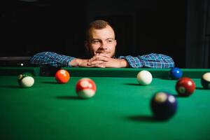 Young man playing billiards in the dark billiard club photo