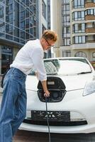 Smiling man unplugging the charger from the car photo