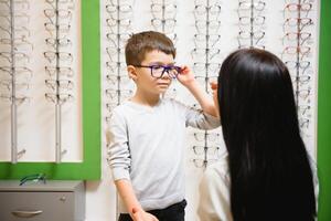 madre con hijo elegir lentes en óptica Tienda foto