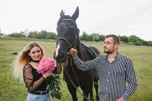 Portrait of happy loving couple spending time with horses on ranch photo