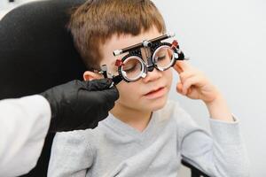 Cheerful child boy in glasses checks eye vision pediatric ophthalmologist photo