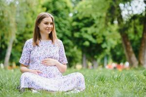 embarazada mujer descansando en el parque foto