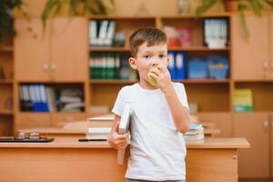 Elementary schoolboy using digital tablet with classmate studying in background at classroom photo