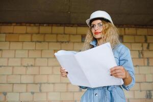 mujer constructor mirando a arquitectónico Plano en nuevo Departamento foto