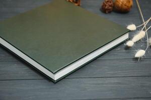 Green wedding or family photo book with leather cover. stylish wedding photo album close up. family photoalbum on wooden background.