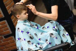 Cheerful Caucasian boy getting hairstyle in barbershop photo