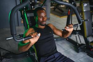 Motivated young black sportsman having workout on rowing machine photo