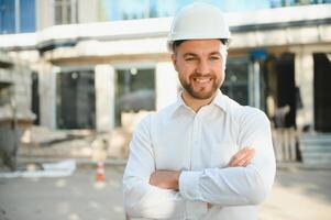 Engineer next to building cranes. Concept - large construction project. Architect directs the construction process. Drawings and tablet in the hands. photo