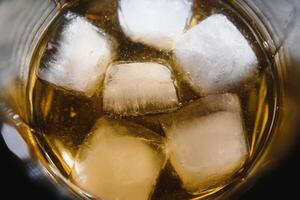 Glass of scotch whiskey and ice over black background photo